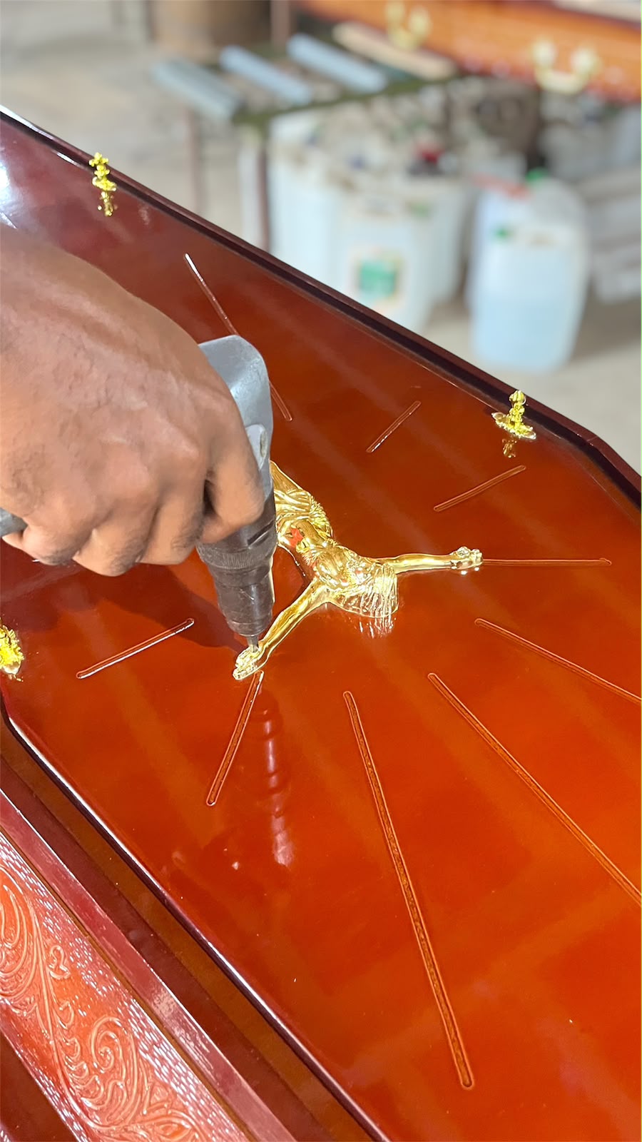 Aplicação artesanal de crucifixo dourado em urna fabricada pela Madeferro